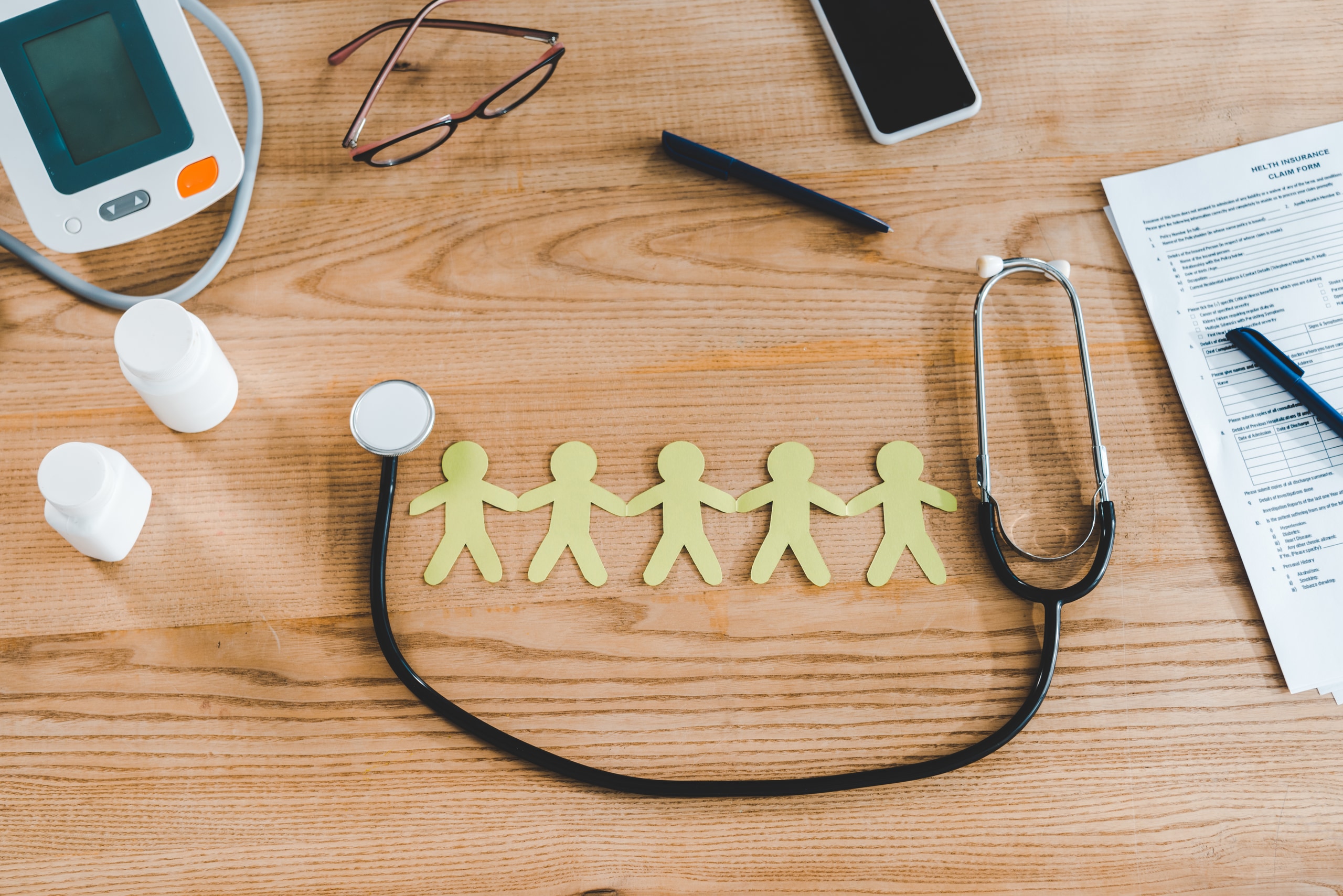 top view of stethoscope near yellow human shapes and smartphone with blank screen top view of stethoscope near yellow human shapes and smartphone with blank screen