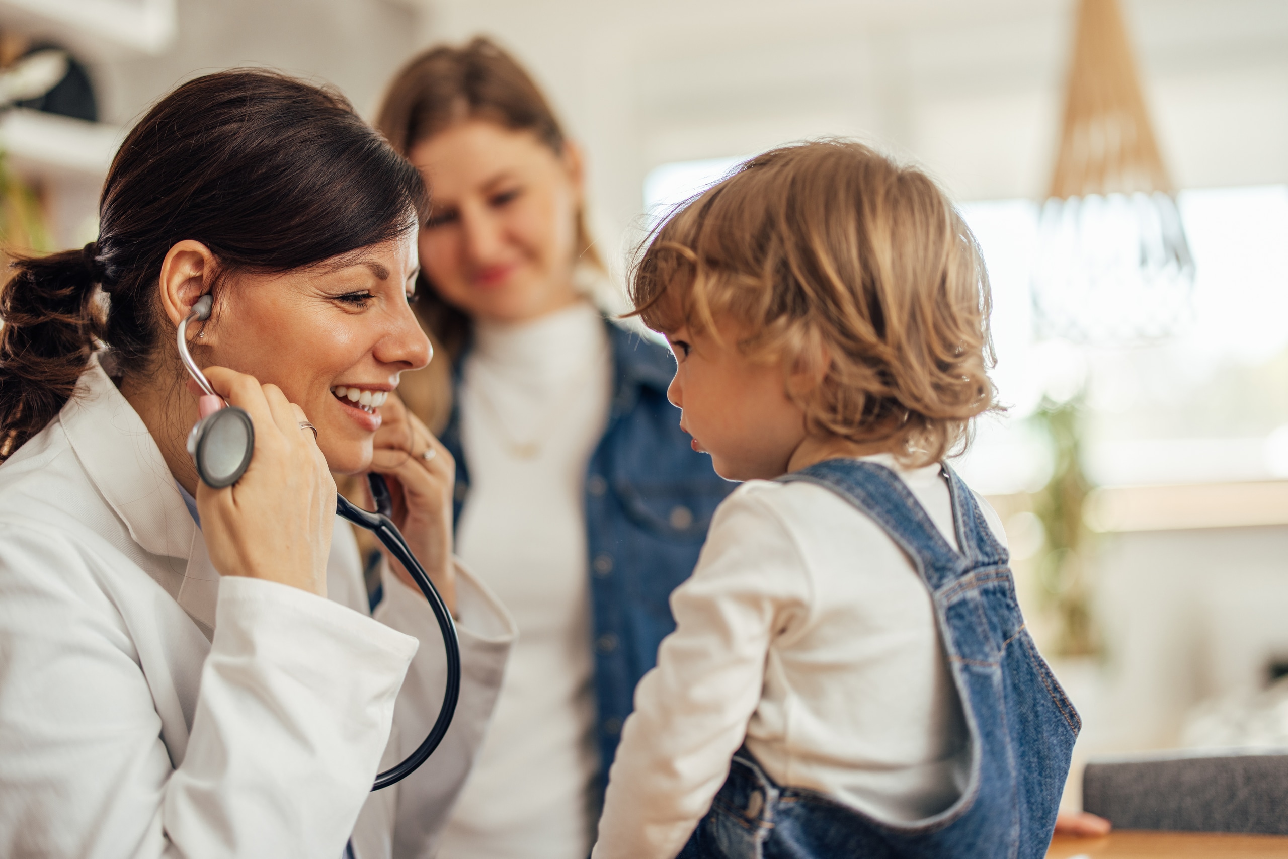 Side view of a smiling female pediatrician putting on a stethosc Side view of a smiling female pediatrician putting on a stethosc