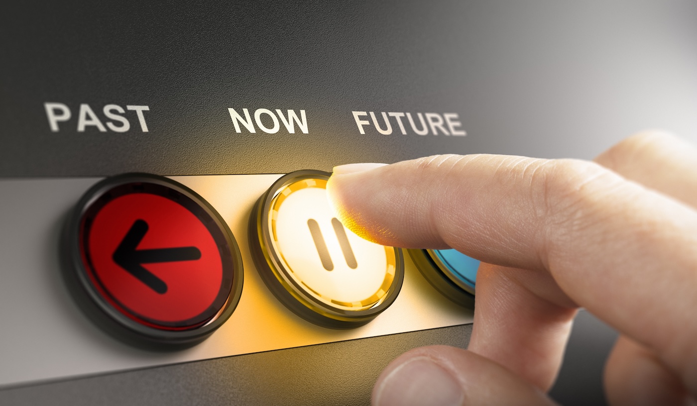 Image 3 Man pressing a yellow button with the word now printed on the top, to stop the time and live in the present moment. Composite image between a hand photography and a 3D background.