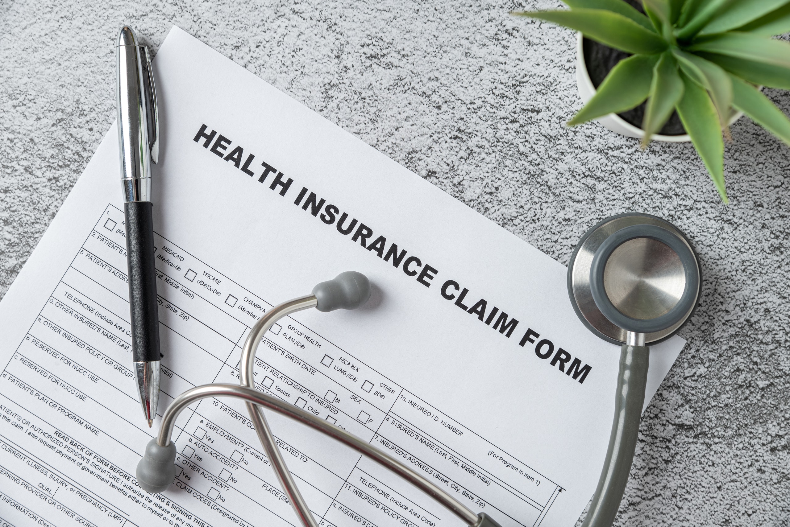 Top view of doctor's stethoscope, pen and health insurance claim form on table Top view of doctor's stethoscope, pen and health insurance claim form on table
