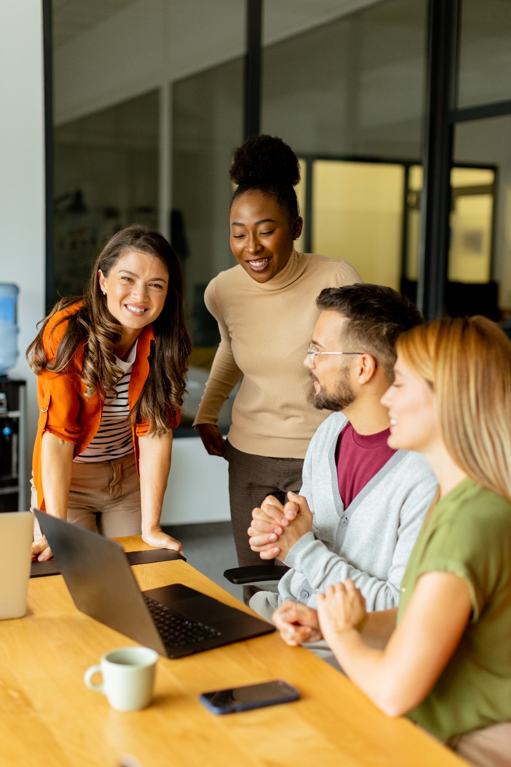 Four colleagues smiling around a table in a bright office