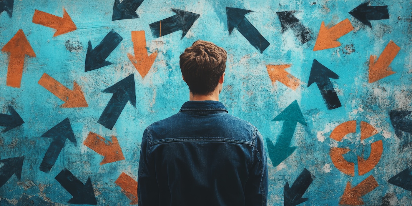 Capa A man stands in front of a wall covered in arrows pointing in different directions. The man is contemplating his next move or decision, as he looks at the wall of arrows