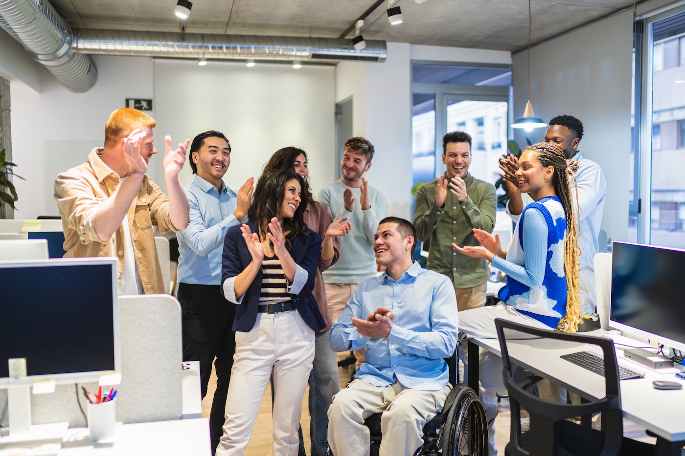 Image 1 Coworkers clapping, celebrating a goal achievement or good news in a modern office, showing teamwork and inclusion