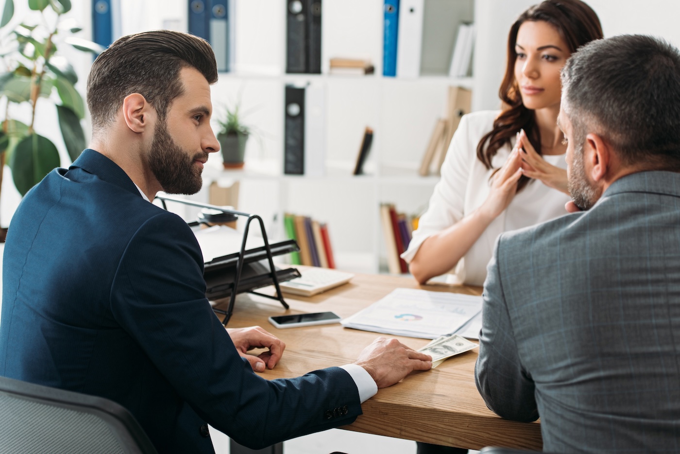Capa selective focus of handsome investors in suits talking with attractive advisor at workspace