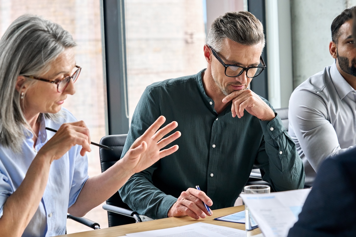 Image 4 Serious mature caucasian male ceo executive manager with male business partner discussing corporation merge plan at board room table. Professional coworkers leaders doing paperwork in modern office.