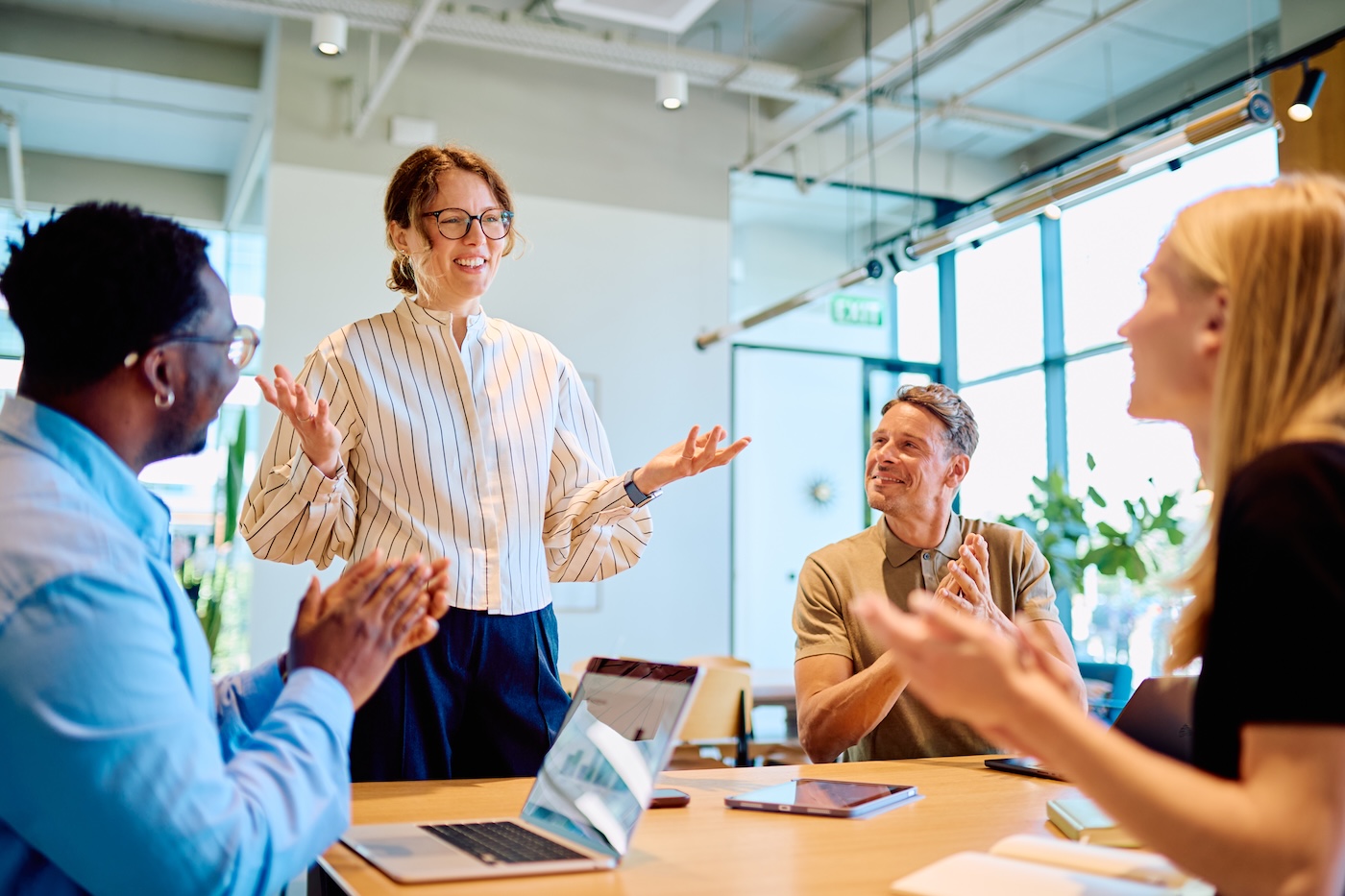 Businesswoman giving presentation receiving applause from diverse team